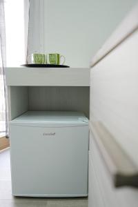 een witte koelkast met twee groene bekers op een plank bij Just Like Home in Napels