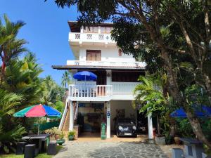 a white house with a car parked in front of it at White Villa in Unawatuna