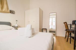 um quarto com uma cama branca, uma mesa e cadeiras em Casa Imperatrice Sissi em Trieste