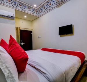 1 dormitorio con 1 cama con almohadas rojas y TV en Hotel Dev Palace, en Sawāi Mādhopur