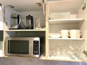 eine Küche mit Mikrowelle, Tellern und Gläsern in der Unterkunft 2-toaline puhkekoht Mai 25 in Pärnu