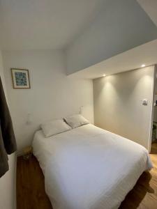 um quarto com uma grande cama branca num quarto em Le petit beauregard em Le Fenouiller