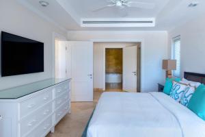 1 dormitorio blanco con 1 cama y TV de pantalla plana en The Crane Resort en Saint Philip