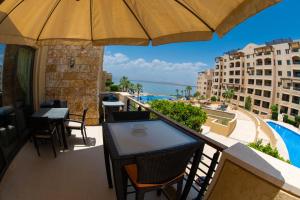 - un balcon avec une table, des chaises et un parasol dans l'établissement Sunset apartment in Samarah Dead Sea resort, à Sowayma