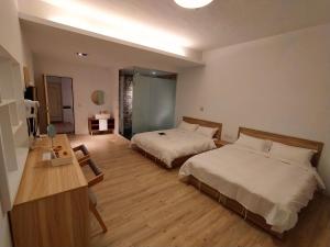una camera d'albergo con 2 letti e una scrivania di Travel Life 源旅生活民宿 a Shuili