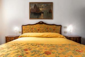 a bed with a yellow blanket and a painting on the wall at Hotel Casa Boccassini in Venice