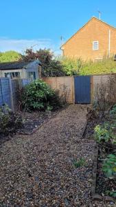 a garden with a fence and a house in the background at Superb 4 Bed 4 Bath House Right by Luton Airport in Luton