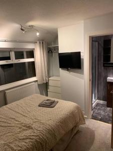 a bedroom with a bed and a flat screen tv at Superb 4 Bed 4 Bath House Right by Luton Airport in Luton