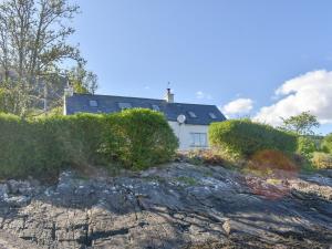 a white house on a hill with bushes at The House On The Slip - Uk43806 in Kylerhea