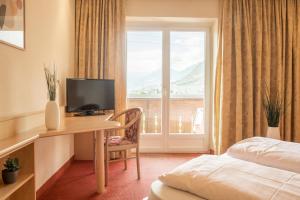 a hotel room with a desk with a television and a window at Hotel Elisabeth in Merano