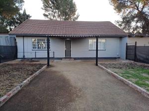 a small white house with a black roof at Mossie Nes - Self Catering in Bloemfontein