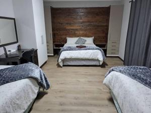 1 dormitorio con 2 camas y pared de madera en Mossie Nes - Self Catering, en Bloemfontein