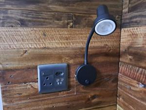 a light on a wooden wall with a socket at Mossie Nes - Self Catering in Bloemfontein