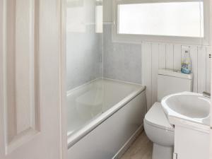 a bathroom with a tub and a toilet and a sink at Bows Pad in Gwithian