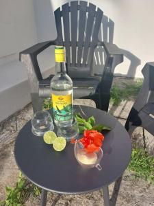 una botella de alcohol y un plato de comida en una mesa en Beau T2 Cosy tout Confort avec terrasse et jardin, en Les Abymes