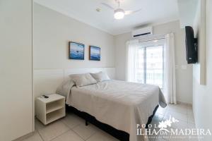 Un dormitorio blanco con una cama y una ventana. en Pool Ilha da Madeira Resort, en Riviera de São Lourenço
