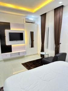 a hotel room with a bed and a flat screen tv at Primal Msquare Apartment Ikoyi in Lagos