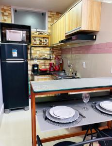 a kitchen with a black refrigerator and plates on a counter at Studio Bangalô Belém Hospedagem in Belém