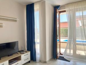 een woonkamer met een televisie en een groot raam bij Apartments in Villas Apolon in Sozopol
