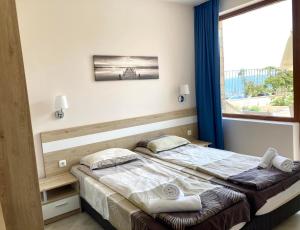 een slaapkamer met een bed en een groot raam bij Apartments in Villas Apolon in Sozopol