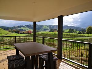 a table on a balcony with a view of the mountains at Karapiro Retreats holiday house in Cambridge