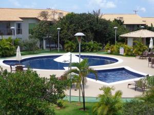 uma piscina num resort com mesas e guarda-sóis em Reserva Imbassaí Apartamento 1 quarto área de churrasco Bl2202 em Mata de São João
