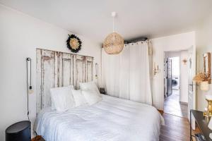 a bedroom with a white bed with a wooden headboard at Charmant Appartement avec Jardin in Suresnes