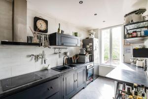 una cucina con lavandino e orologio sul muro di Charmant Appartement avec Jardin a Suresnes