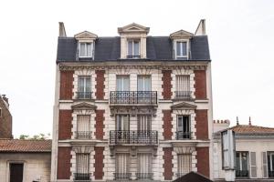 - un grand bâtiment en briques avec des fenêtres et des balcons dans l'établissement Charmant Appartement avec Jardin, à Suresnes