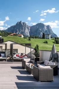 eine Terrasse mit Sofas, Stühlen und Bergen im Hintergrund in der Unterkunft Martina Breakfast Lodge in Kastelruth