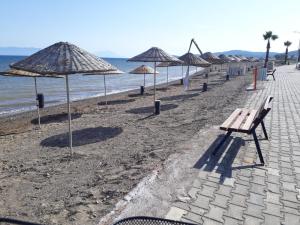 una fila di panchine e ombrelloni su una spiaggia di SEFERİHİSAR ÜRKMEZ DE KİRALIK YAZLIK a Ürkmez