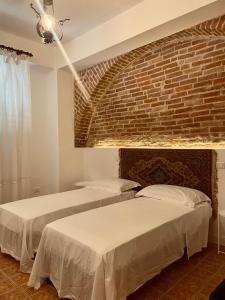 two beds in a room with a brick wall at Don Ciccio GH in Bova Marina