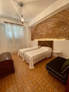 sypialnia z 2 łóżkami i ceglaną ścianą w obiekcie Don Ciccio GH w mieście Bova Marina