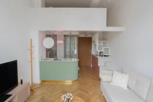 a living room with a white couch and a kitchen at L’appartement Korzó in Satu Mare