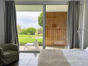 1 dormitorio con cama, silla y puerta corredera de cristal en ArtbyPraXis, en Playa del Gobernador