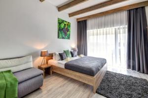 um quarto com uma cama, um sofá e uma janela em Penzión Čerešňový Sad & Wellness em Mengusovce