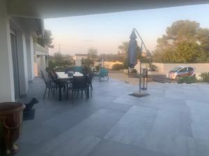 une terrasse avec une table, des chaises et un parasol dans l'établissement maison piscine, à Alès