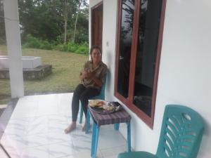 Una donna seduta su una sedia in veranda di Rice field guest house a Kelimutu