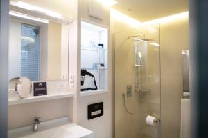 a bathroom with a shower and a sink with a mirror at The Dome Hotel in Satu Mare