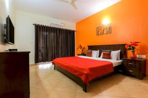 a bedroom with a large bed with orange walls at Royale Holiday Villa - 4BHK, Baga in Baga