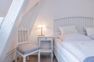 a white bedroom with a bed and a table with a chair at fewo1846 - Im Sonnenhof - komfortable 2-Zimmer-Wohnung im Stadtzentrum in Flensburg