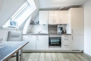 フレンスブルクにあるfewo1846 - Im Sonnenhof - komfortable 2-Zimmer-Wohnung im Stadtzentrumの白いキャビネットとテーブル付きのキッチン