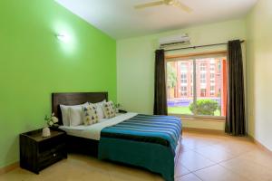 Royale Holiday Villa - 4BHK, Baga في باغا: غرفة نوم بها سرير وبجدران خضراء ونافذة