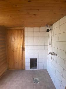 a bathroom with a shower and a tiled wall at MK Kodumajutus in Võrumõisa