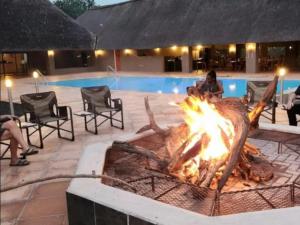 a fire pit in front of a swimming pool at Thandolwami Bushlodge & Spa in Hoedspruit