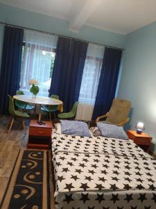 1 Schlafzimmer mit 2 Betten, einem Tisch und blauen Vorhängen in der Unterkunft Noclegi Zdzisław Sieradzki in Zbiczno
