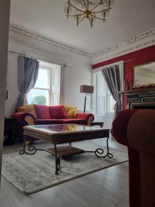 a living room with a red couch and a coffee table at Cameron House - spacious B listed building, near Falkland, Central East Scotland in Auchtermuchty