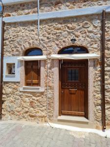 a stone building with a wooden door and two windows at Village home in Chios