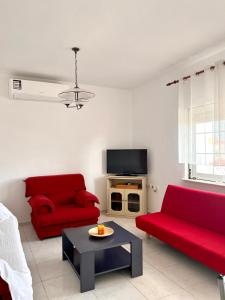 a living room with two red couches and a tv at Dimitra House Entire apartment with balcony and view in Pherrai