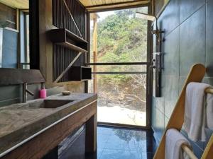 La salle de bains est pourvue d'un lavabo et d'une grande fenêtre. dans l'établissement Mawo house, à SantʼAna